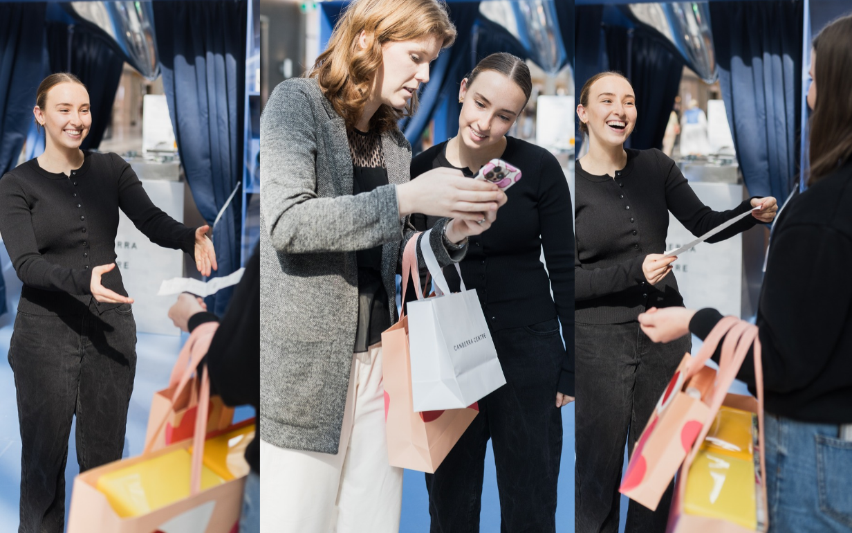 Image of a customer handing over a receipt while holding shopping bags at the Spend to Win pop-up.